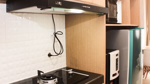 A kitchen with a gas stove, a microwave, and a refrigerator. - Elegant And Strategic Loft Studio Apple 1 Condovilla Apartment (Jakarta)
