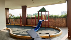 A playground with a slide, swings, and climbing structures. - Comfort And Warm Studio At Serpong Greenview Apartment (South Tangerang)