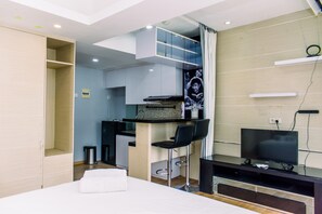 A modern hotel room with a bed, a TV, a kitchenette, and a small bar area. - Comfort And Warm Studio At Serpong Greenview Apartment (South Tangerang)