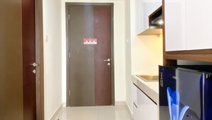 Cocina moderna con armarios blancos, refrigerador de acero inoxidable y encimera de madera.