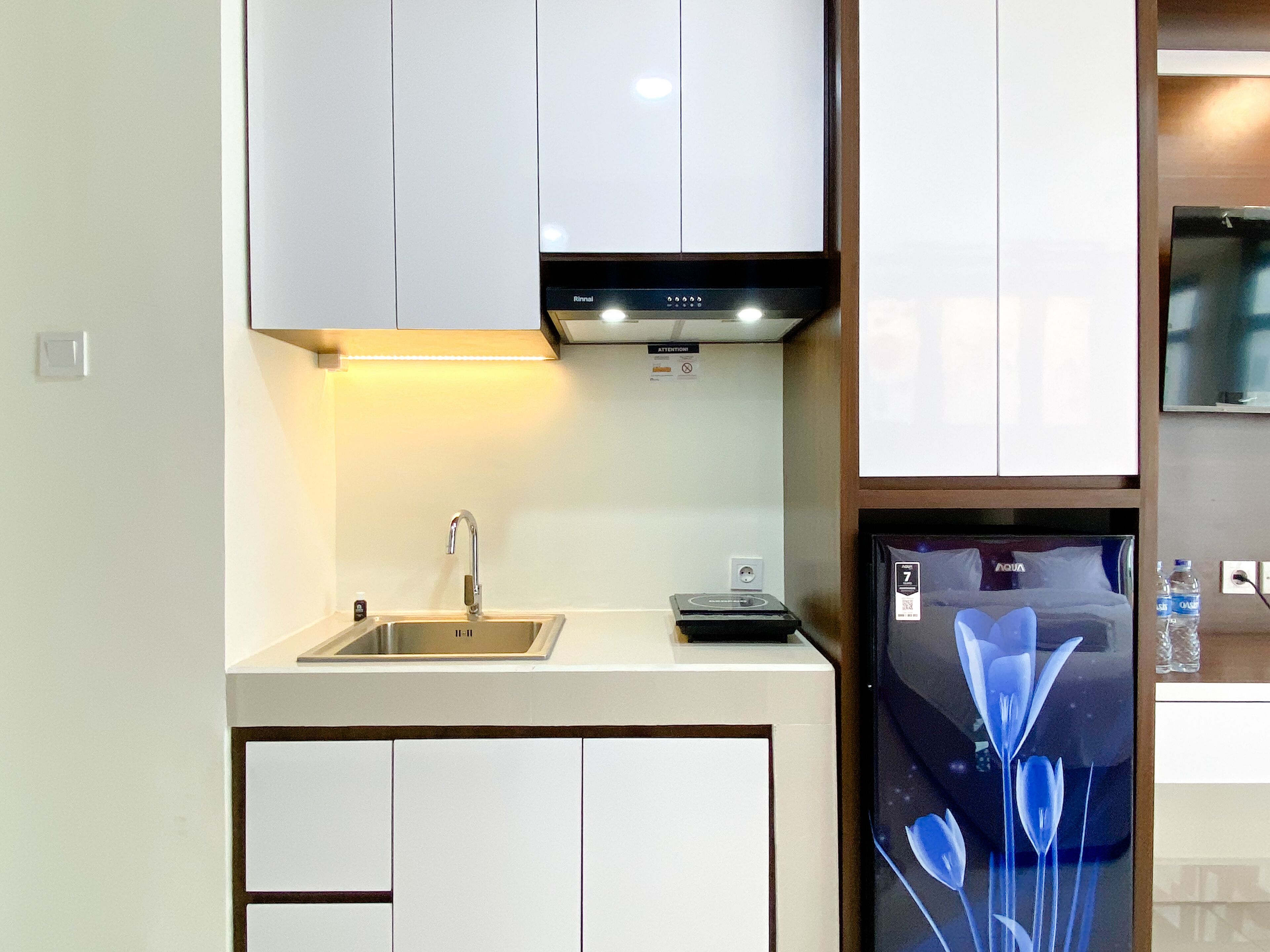 Una cocina moderna con armarios blancos, un lavamanos de acero inoxidable y un refrigerador negro con diseño floral.