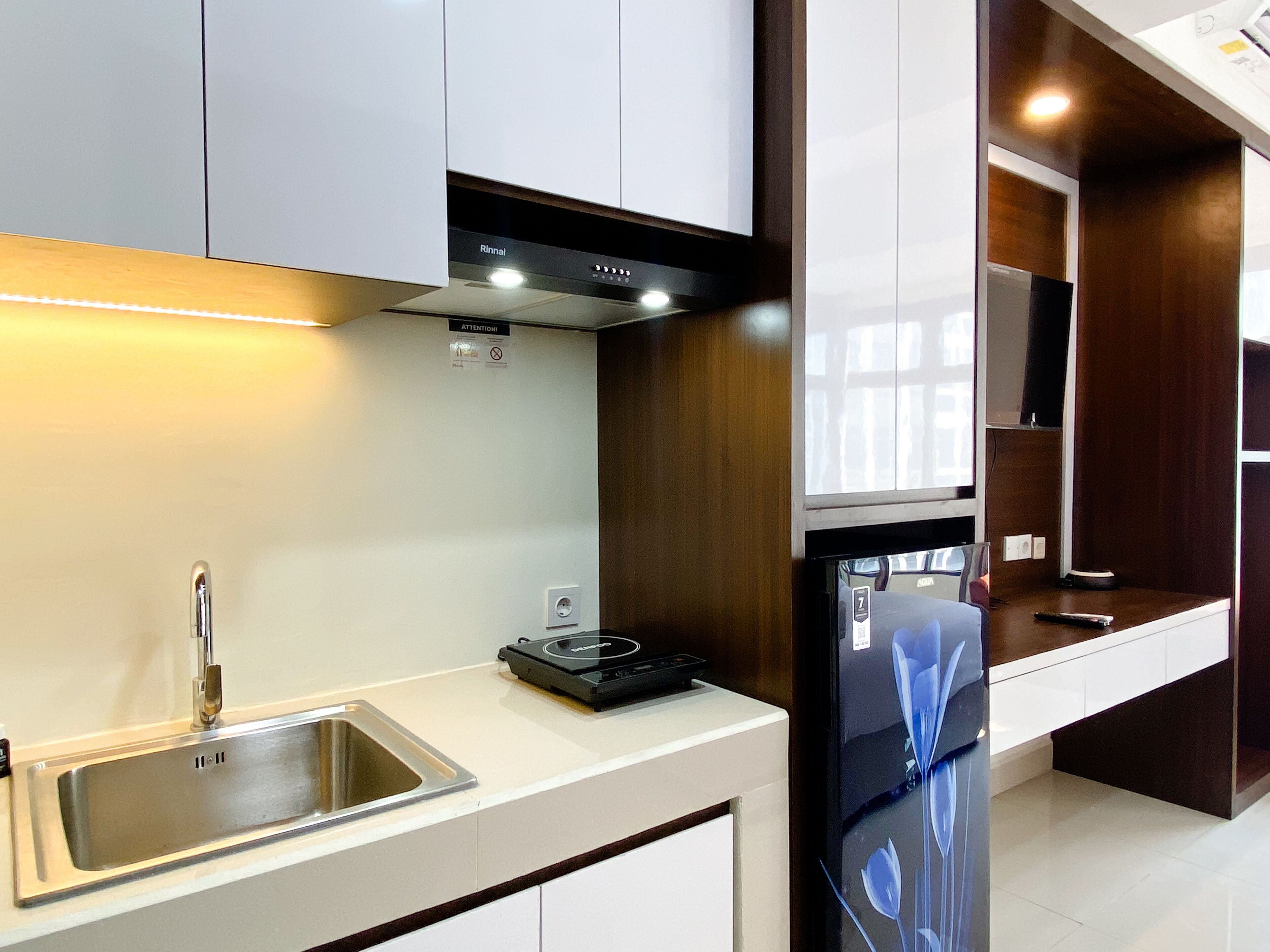 Una cocina moderna con gabinetes blancos, un lavamanos de acero inoxidable y un horno empotrado.