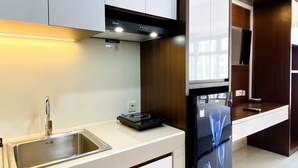 Una cocina moderna con gabinetes blancos, un lavamanos de acero inoxidable y un horno empotrado.