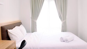 Une chambre d’hôtel avec un lit, une table de chevet en bois, une chaise et des rideaux.