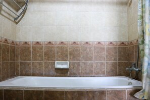 Bathroom features a bathtub and shower area with a decorative tile border.