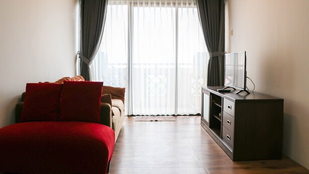 Una camera d'albergo con un letto, una TV su un mobile e un balcone con tende.