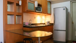 Una cucina con mobili in legno, un'isola in vetro, un forno a microonde, un frigorifero e un lavello.