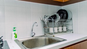 Een keuken met een roestvrijstalen spoelbak, een afwassysteem met borden en bekers, en een fles afwasmiddel.