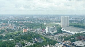 Vista aerea di una città con un grattacielo in evidenza, un’ampia area di parcheggio e edifici residenziali e commerciali circostanti.