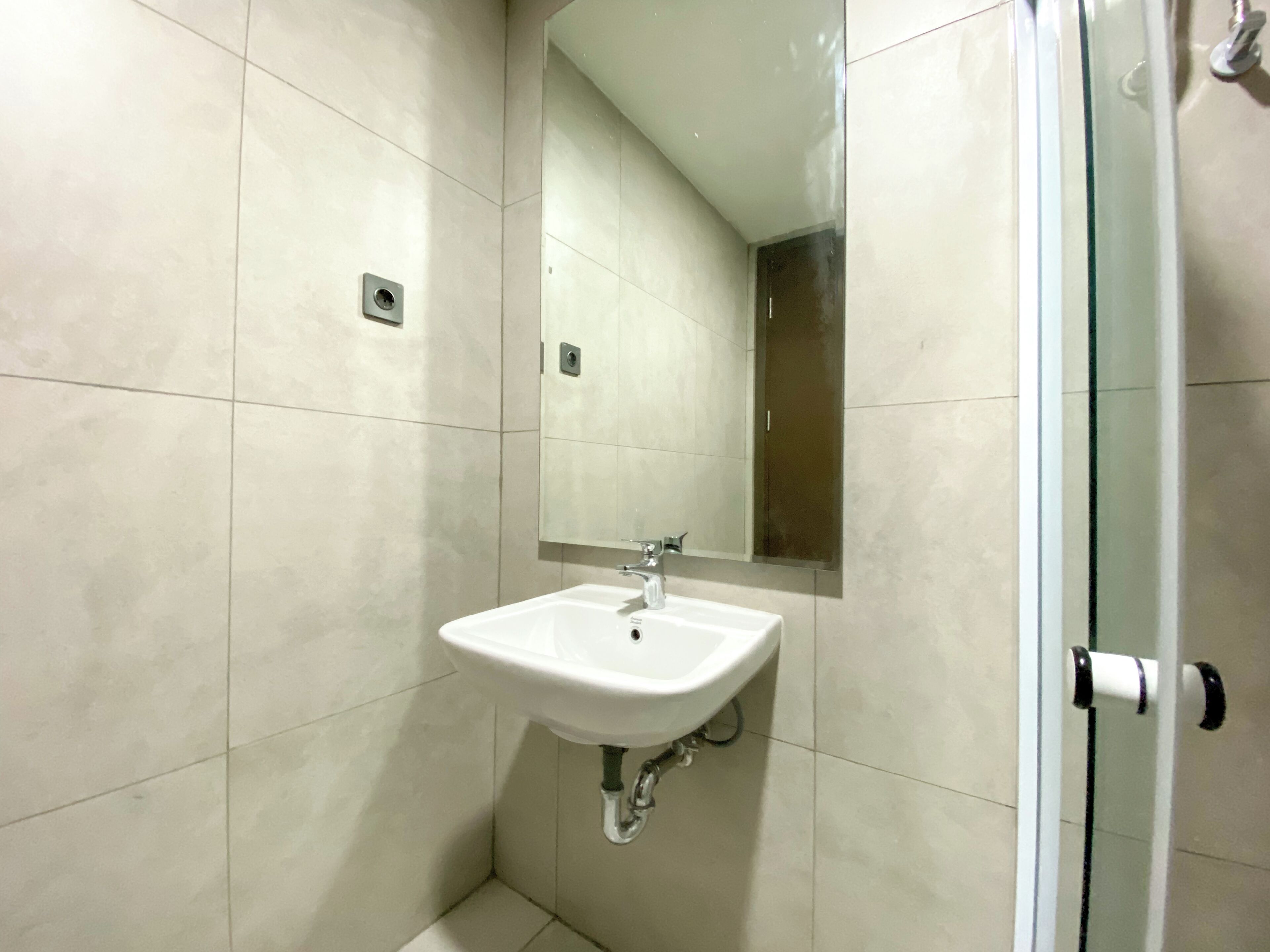 A bathroom with a white sink, a mirror, and a shower door.