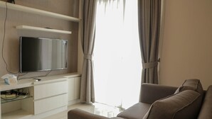 A modern living room with a flat-screen TV, white entertainment unit, and a sofa. - Scenic And Homey 2Br Signature Park Grande Apartment (Jakarta)