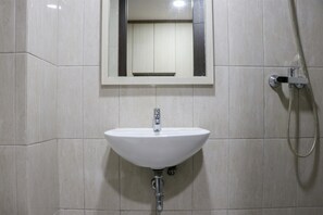 A bathroom with a white sink, a mirror, and a shower. - Elegant And Nice Studio Room At Citra Living Apartment (Jakarta)
