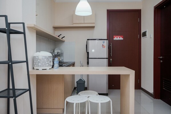A compact kitchen with a wooden countertop, a refrigerator, and a sink. There are stools and a shelf with kitchenware. - Wonderful 1Br Asatti Apartment Vanya Park Bsd (Pagedangan)