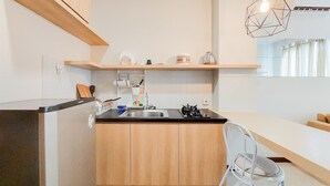 Une cuisine moderne avec des meubles en bois, un plan de travail noir, une cuisinière à gaz et un luminaire géométrique suspendu.