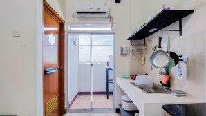 A compact kitchen with a built-in air conditioner, a sink, and a small window overlooking the balcony. - Nice Studio At Loftvilles City Apartment (South Tangerang)