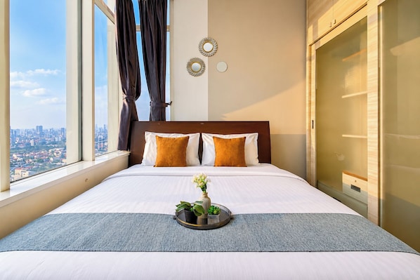 A hotel room with a large bed, a view of the city, and a window with curtains. - Comfortable And High Floor 2Br Apartment At Thamrin Residence (Jakarta)