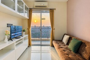 A modern living room with a sofa, a flat-screen TV, and a balcony with curtains. - Comfortable And High Floor 2Br Apartment At Thamrin Residence (Jakarta)