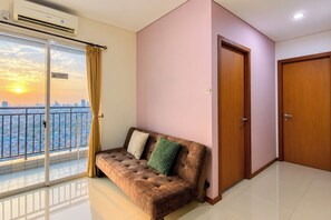 A room with a sofa, a sliding glass door, and a view of a cityscape.