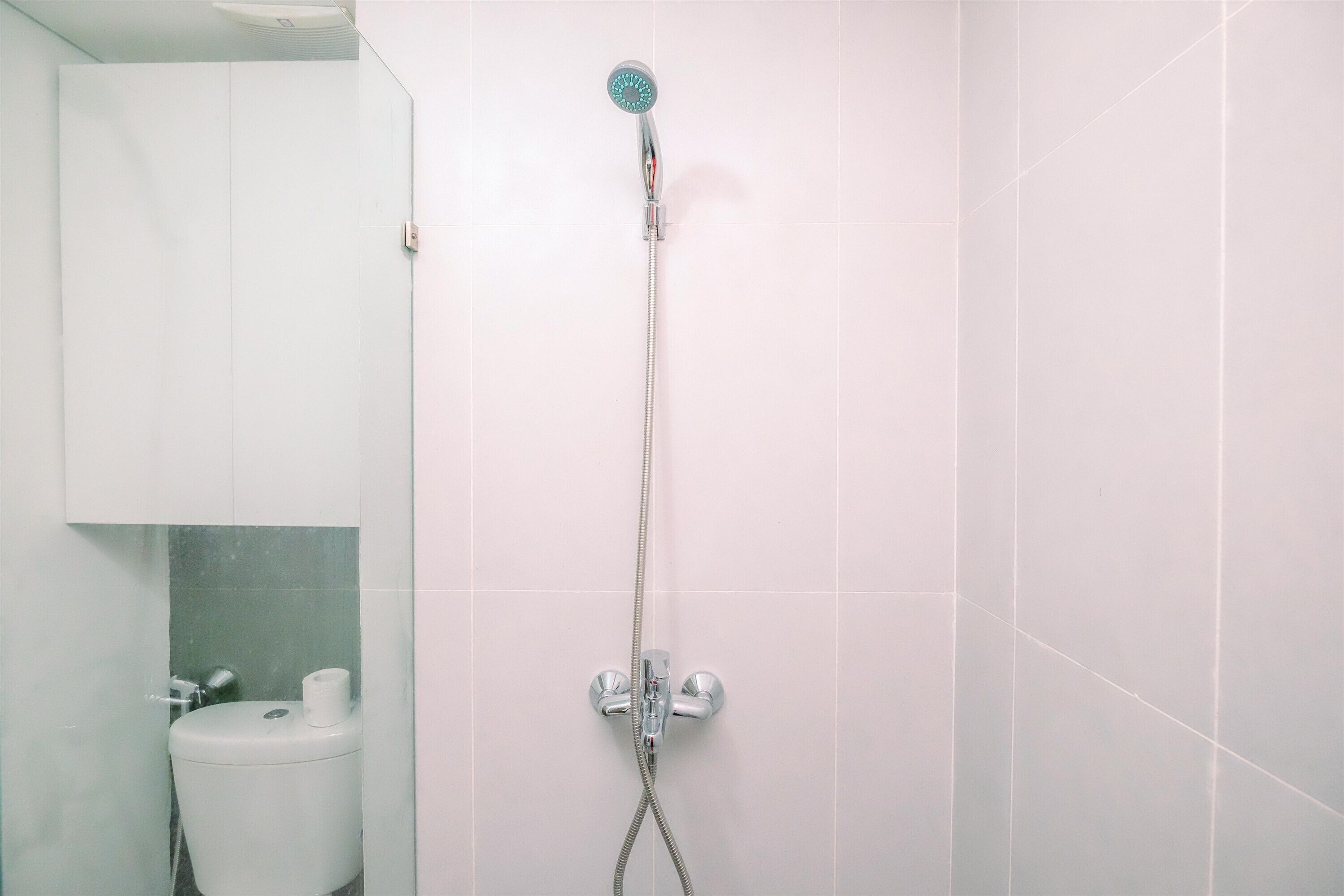 Un baño con ducha, inodoro y un armario.
