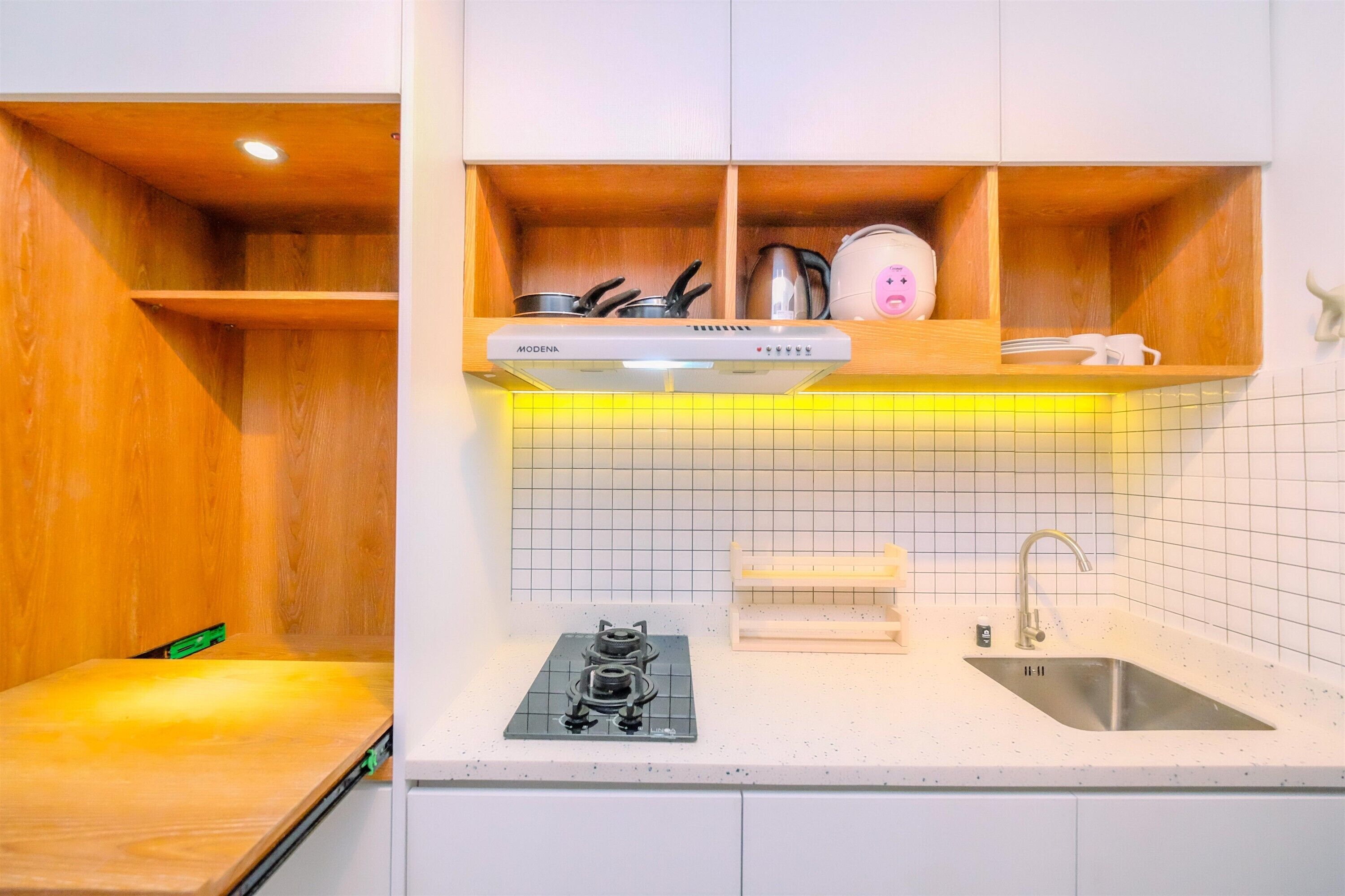 Una cocina compacta con estufa integrada, un lavamanos y repisas de madera.