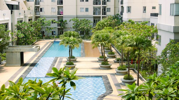 A residential building with a swimming pool surrounded by greenery and potted plants. - Good Deal And Homey 1Br Maple Park Sunter Apartment (Jakarta)