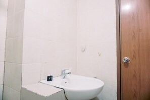 Bathroom features a white sink and single faucet, with a separate room accessible through the wooden door.