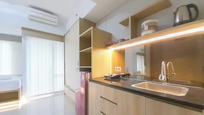 A modern kitchen with a built-in sink, a refrigerator, and a countertop with a kettle and a coffee maker. - Cozy Designed Studio At Taman Melati Sinduadi Apartment (Pogung Lor)