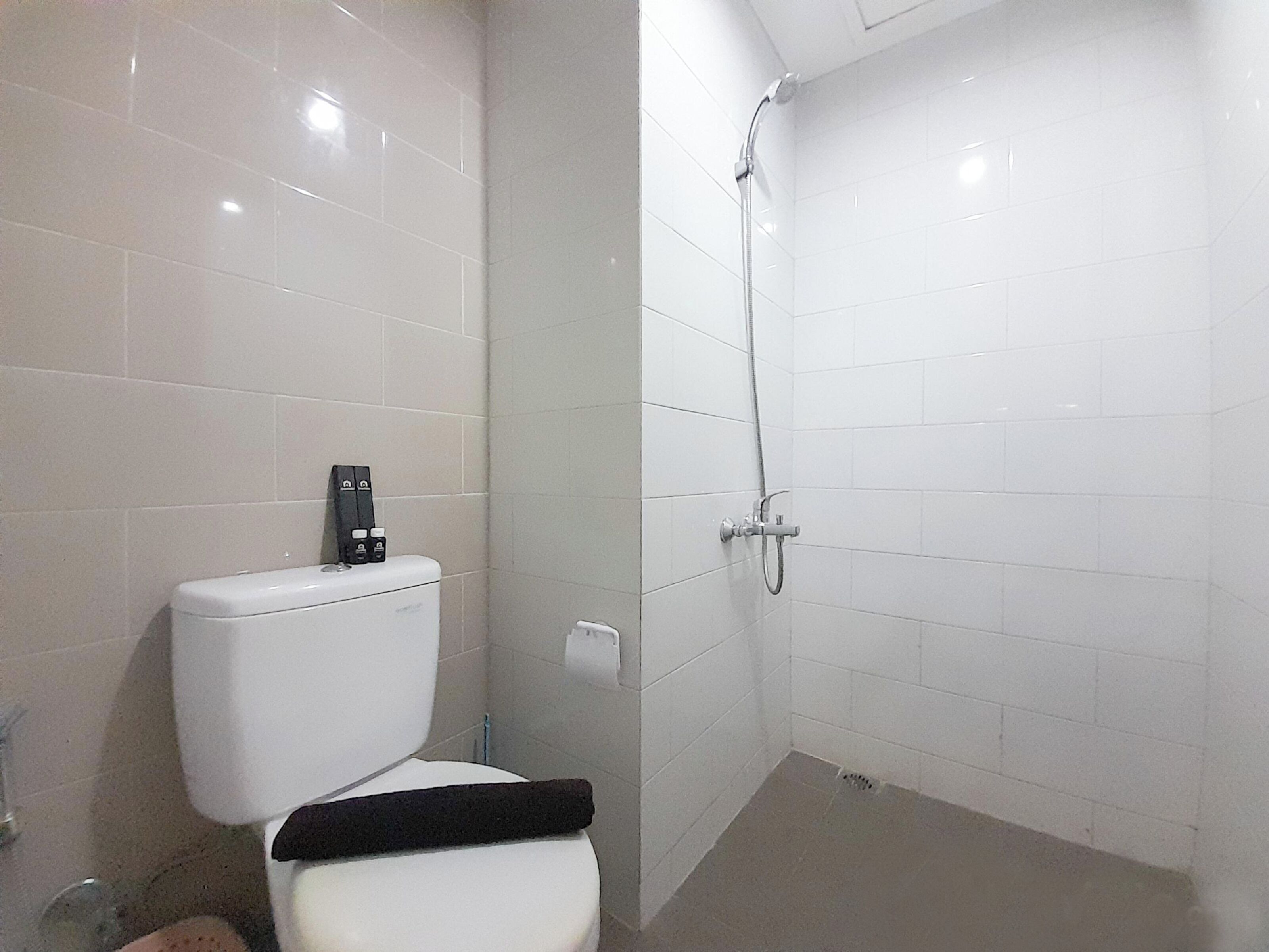 A bathroom with a toilet, a shower, and a toilet paper holder.