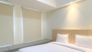 A modern hotel room with a large bed, a headboard, and a window with blinds. - Comfort Stay And Homey 2Br Pollux Chadstone Apartment (Cikarang)