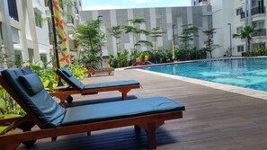 A poolside area with wooden deck, lounge chairs, and a swimming pool.