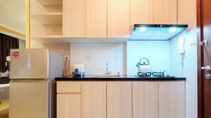 Una cocina compacta con armarios de madera, un refrigerador empotrado, una estufa a gas y un lavamanos.
