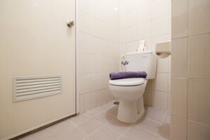 A small, clean bathroom with a toilet, a hand dryer, and a vent on the wall.