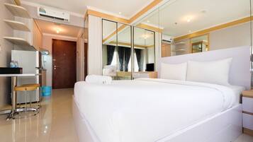 A hotel room with a large bed, a desk with a chair, a mirror, and a wardrobe.