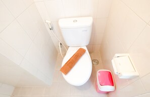 A compact bathroom with a toilet, sink, and trash bin, featuring a towel.