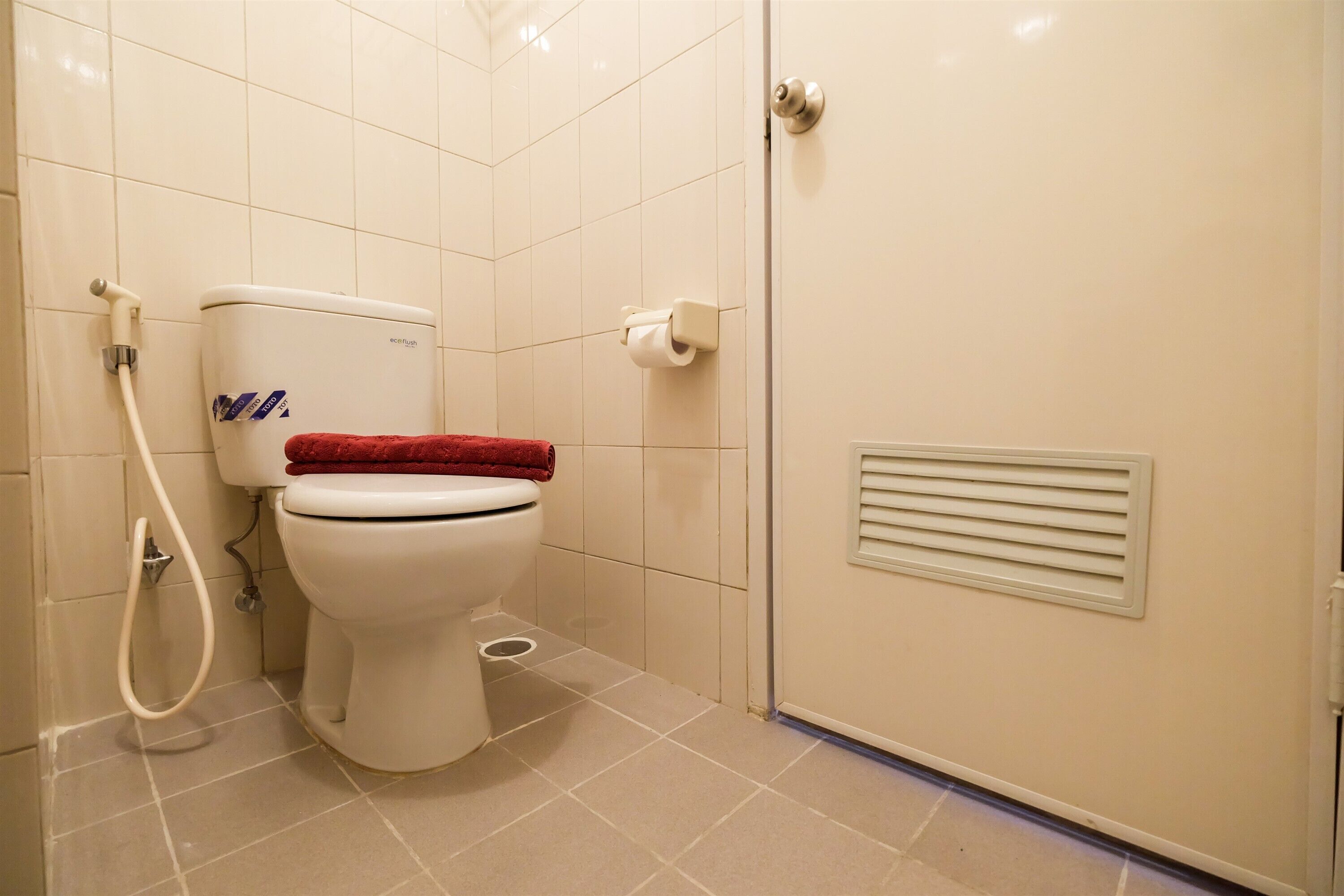 A bathroom with a toilet, a shower, and a toilet paper holder.
