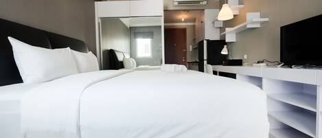 A modern hotel room with a large bed, a TV, a desk, and a wardrobe.