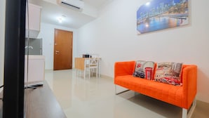 A modern living room with a bright orange sofa, a dining table with chairs, a white cabinet, and a cityscape painting on the wall. - Cozy 2Br Signature Park Grande Apartment Mt Haryono (Jakarta)