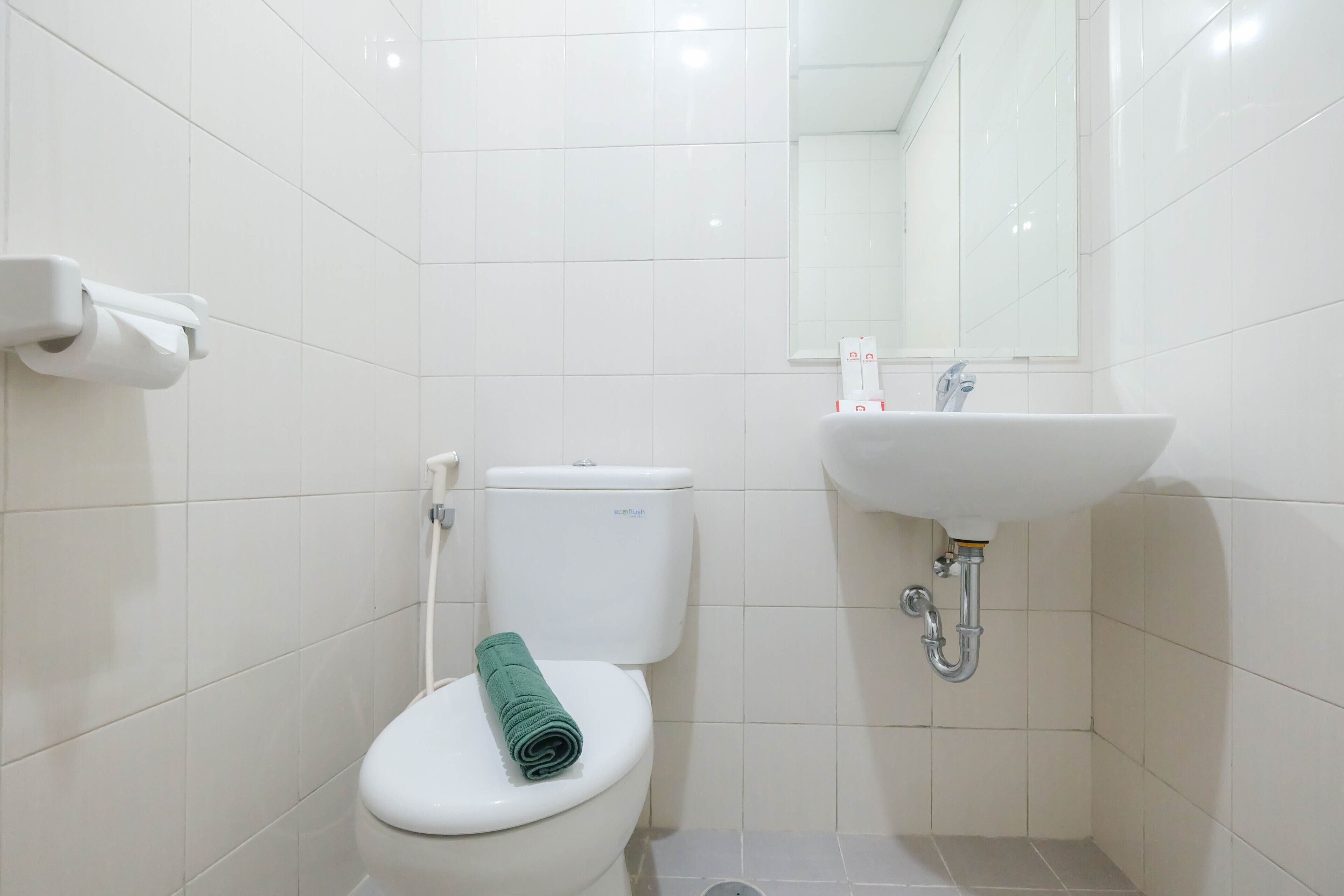 A small, clean bathroom with a toilet, sink, and mirror.