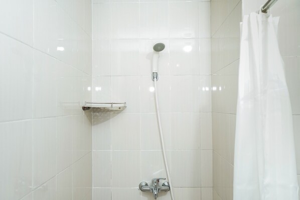 A shower with a handheld showerhead, a wall-mounted faucet, and a shower control panel. - Homey 1Br At Signature Park Grande Apartment (Jakarta)