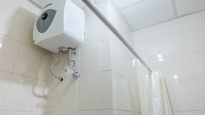 Ein Duschbereich mit Warmwasserbereiter, Rohren und einer Duschvorhang.