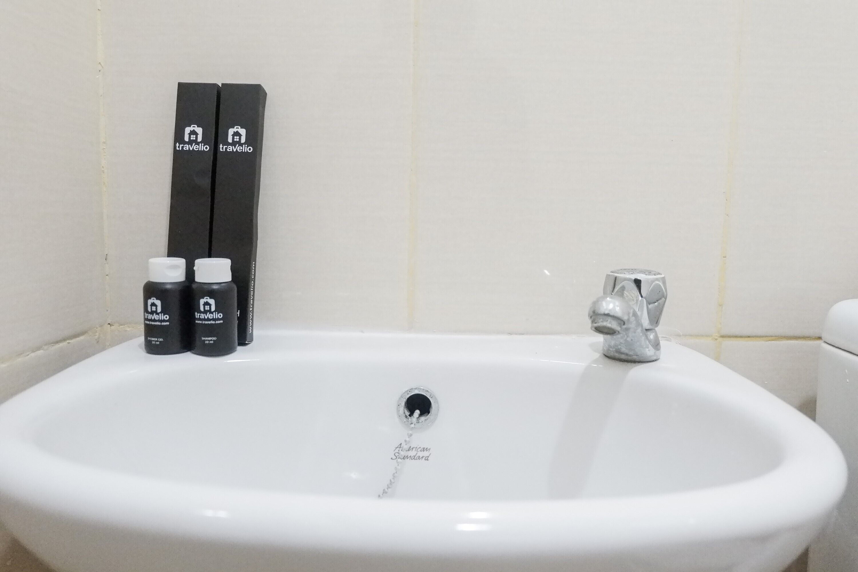 A white bathroom sink with two black toiletries and a silver faucet.