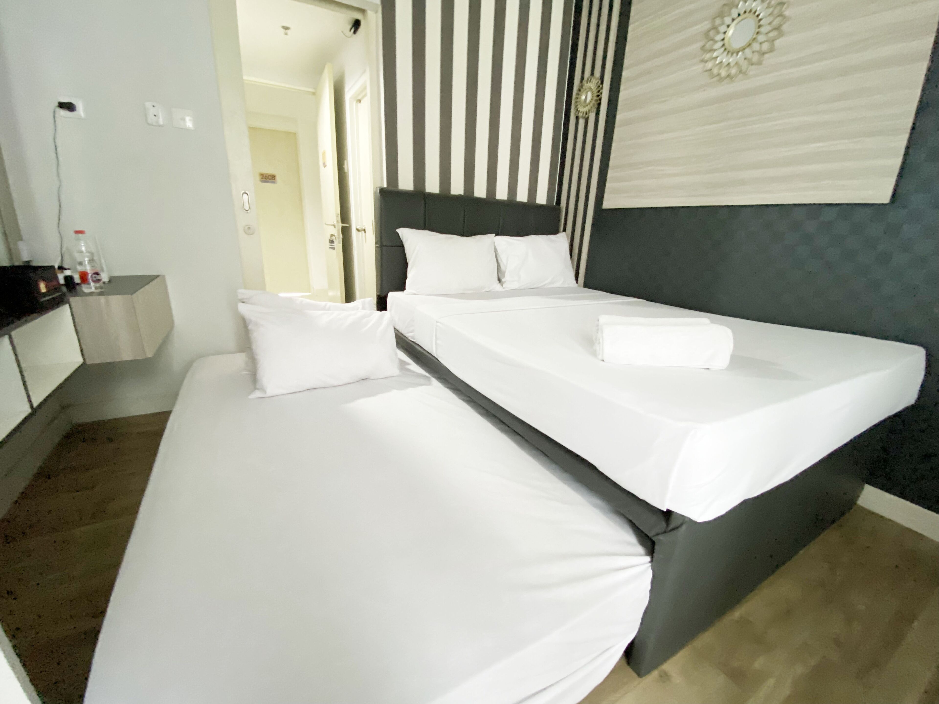 A hotel room with a bed, a bedside table, and a mirror.