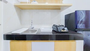 A compact kitchen with a black countertop, a sink, a toaster, and a refrigerator.