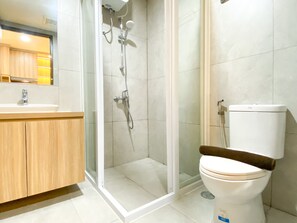 Bathroom features a glass-enclosed shower with handheld and overhead showerheads, a toilet, and a vanity with a mirror.