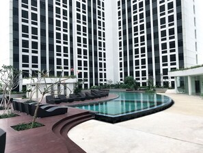 Experience a serene outdoor space with a curved pool and lounge seating surrounded by trees.