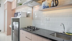 A modern kitchen with a built-in stove, microwave, and refrigerator. - Warm And Minimalist Studio Transpark Bintaro Apartment (South Tangerang)