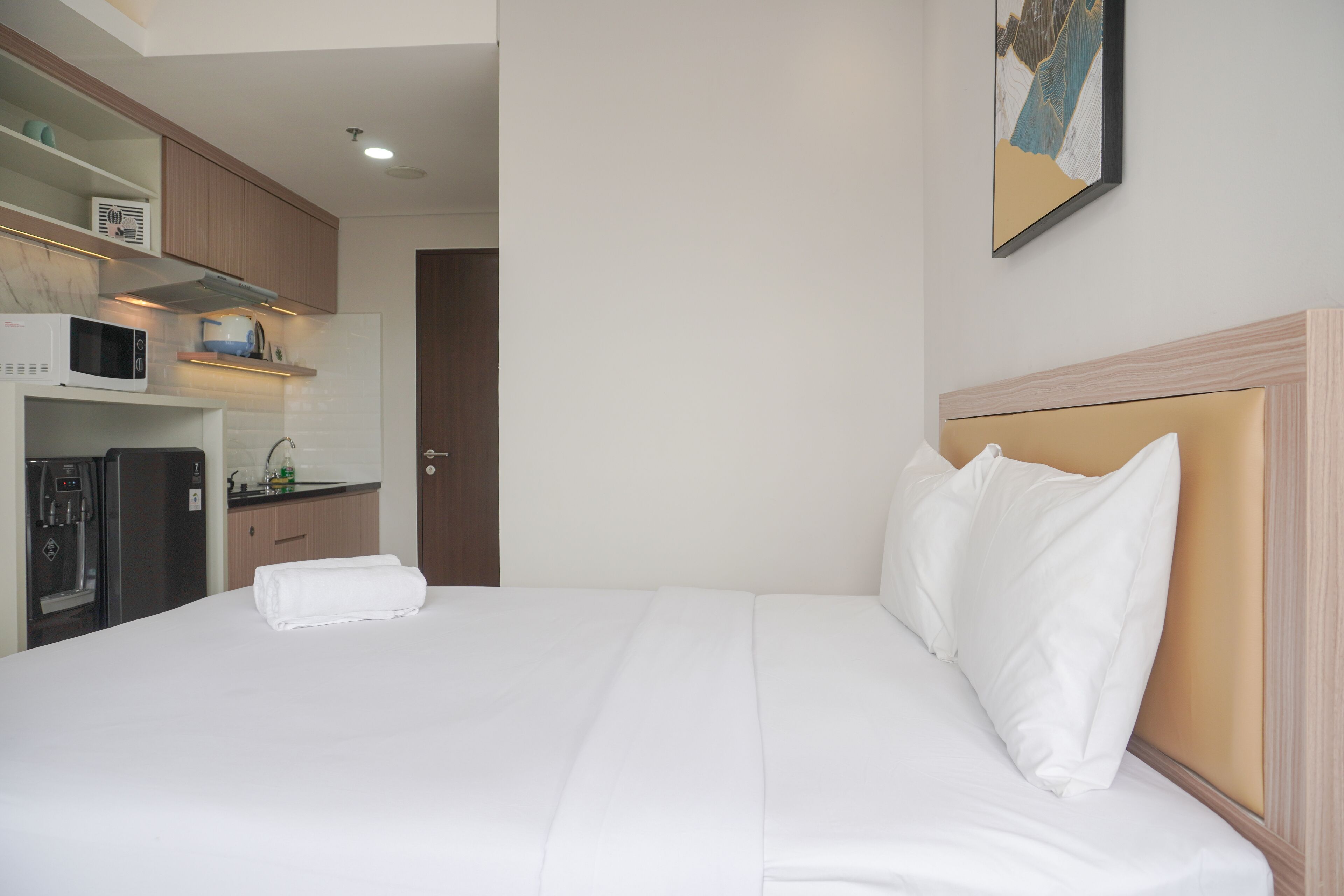 A hotel room with a bed, a microwave, a refrigerator, and a small kitchenette.