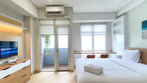 Una habitación de hotel moderna con cama, televisor, escritorio y balcón.