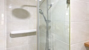A modern shower enclosure with a handheld showerhead and a fixed overhead showerhead.