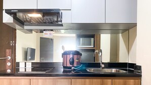 A compact kitchen with a stainless steel range hood, a microwave, a sink, and a rice cooker.